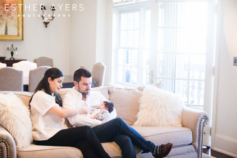 mom and dad looking at newborn baby boy on couch in living room