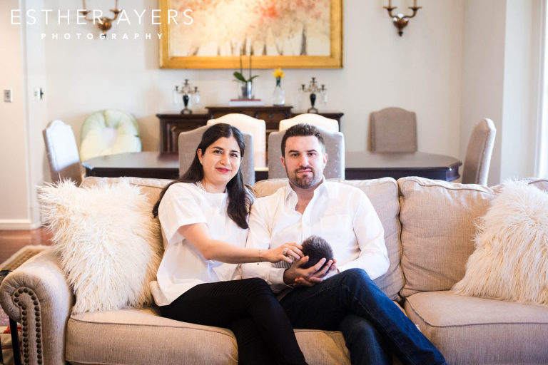 mom and dad sitting on couch holding newborn baby boy