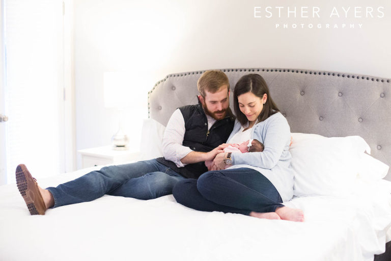 first time mom and dad on bed with newborn baby girl